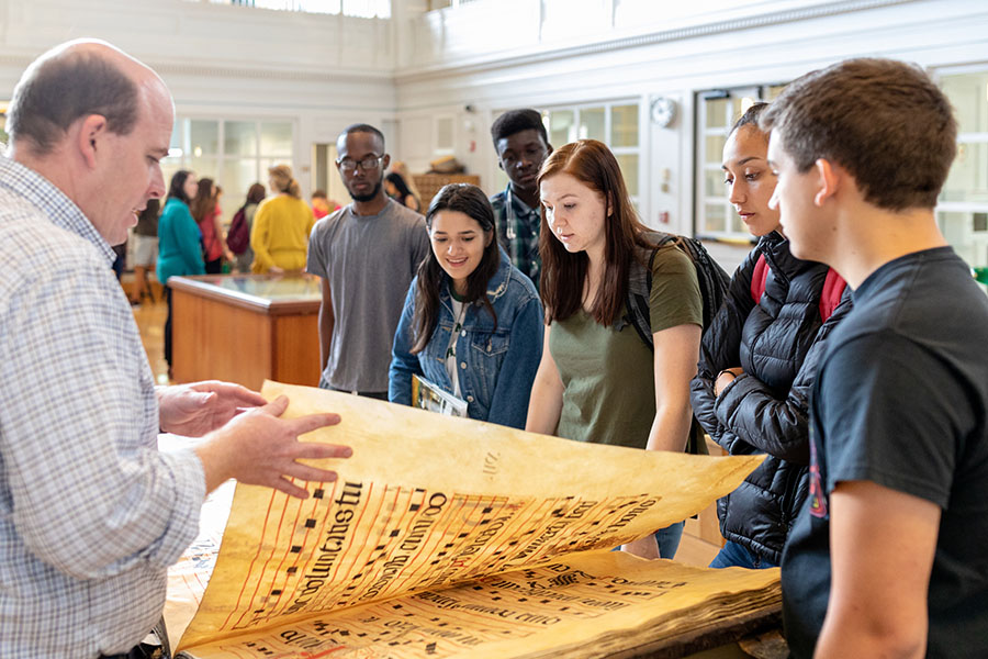 Students and faculty look at a manuscript in the rare books library