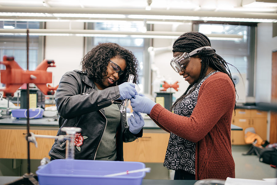 Two female students conduct an experiment in a lab